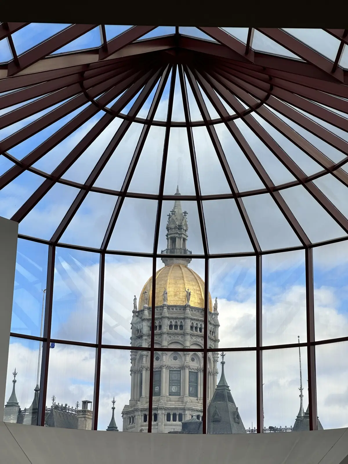 The Capitol's gold dome seen through the glass atrium of the Connecticut Legislative Office Building